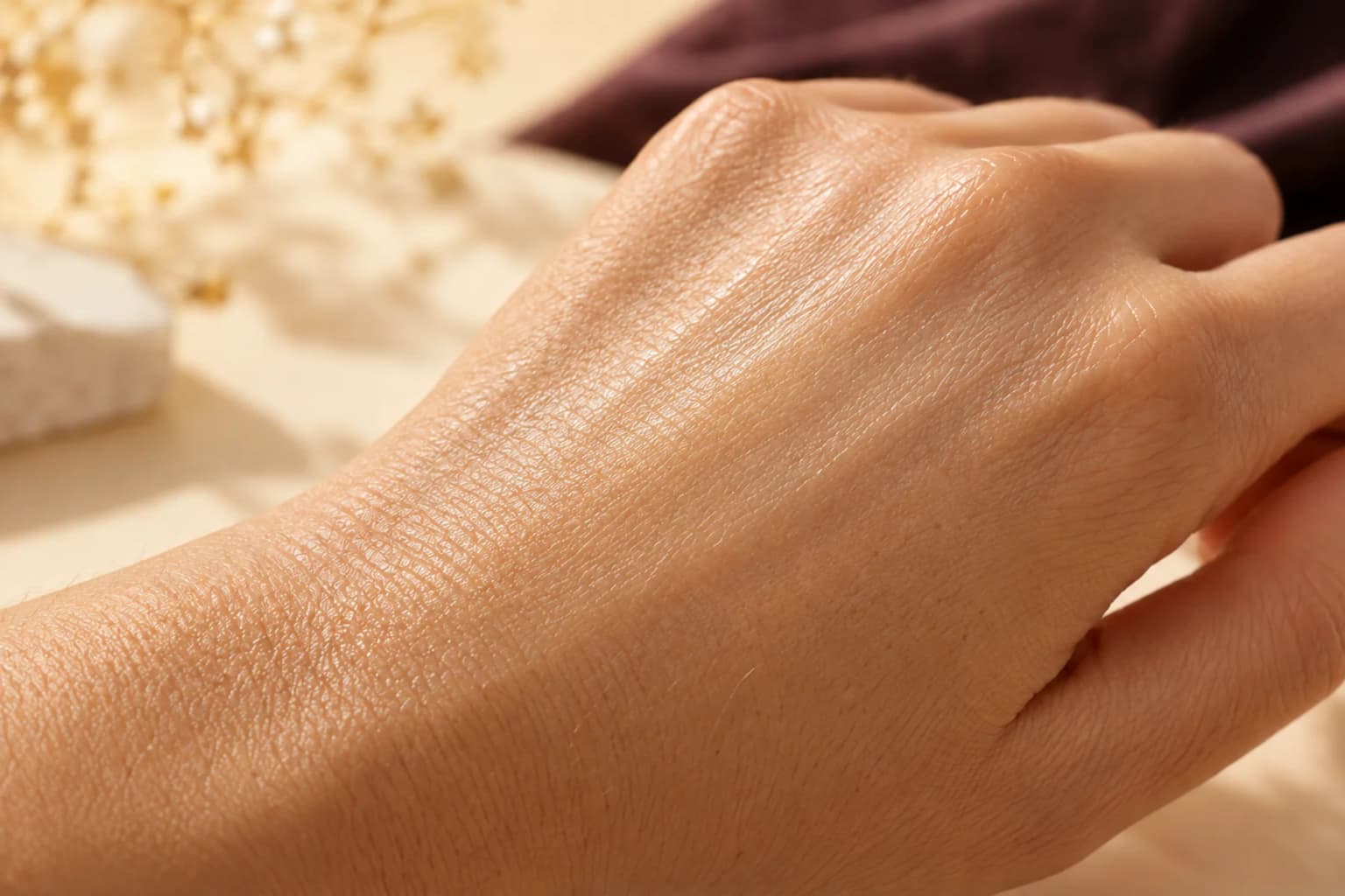 A thin softly luminous cream layer on a naturally textured hand. Editorial illustration, not a measured result.
