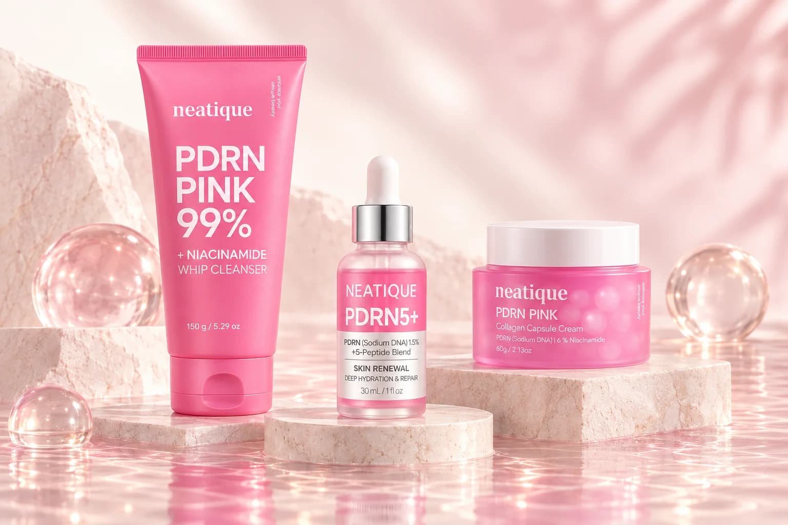 Neatique PDRN cleanser, serum and cream arranged together on pale stone platforms.